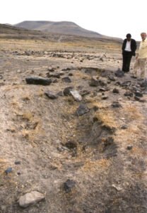 Hole in the ground and broken pieces of rock where a tombstone had been